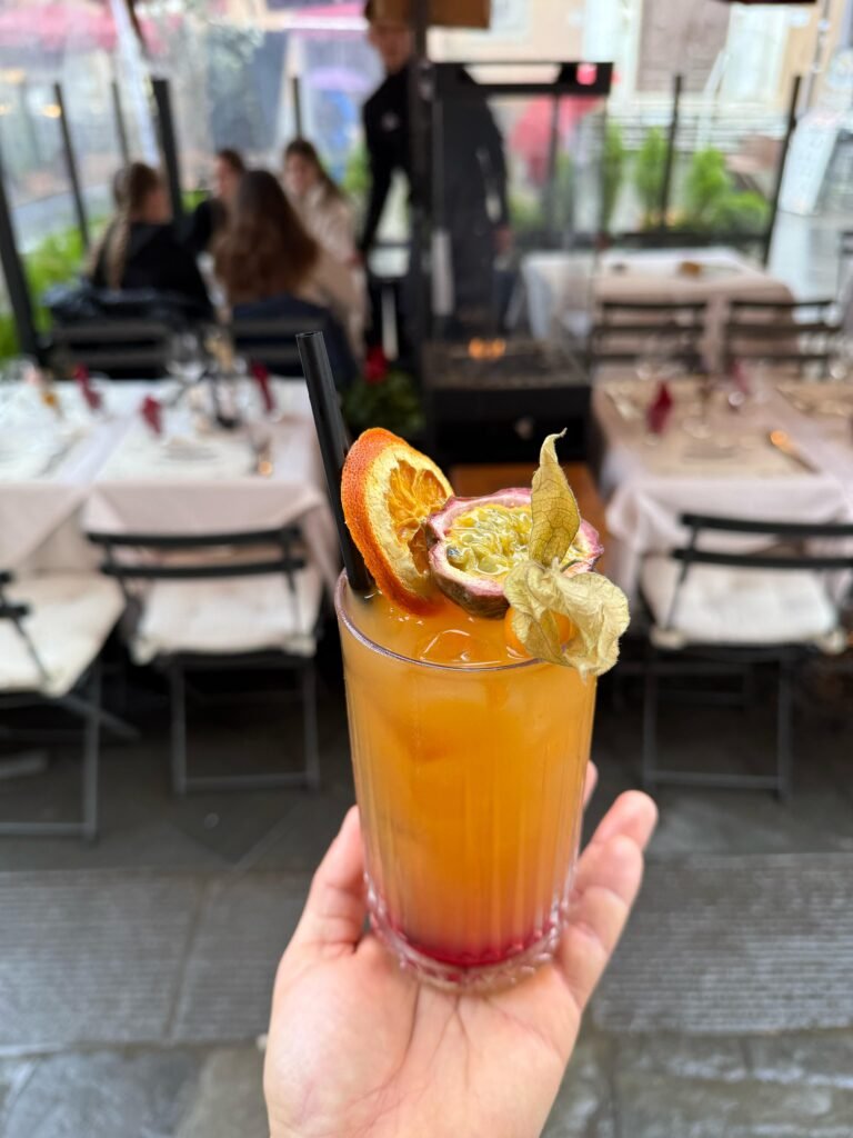 cocktail colorato servito con frutto della passione fresco e arancia essiccata