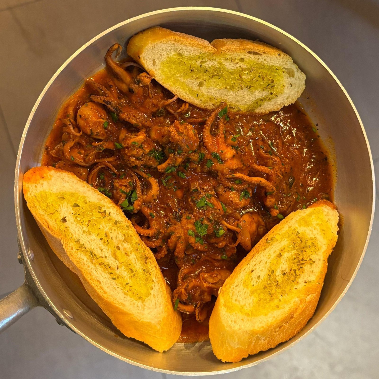 Calamaretti in umido alla genovese serviti con crostini all'aglio, specialità di mare
