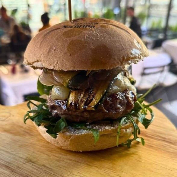 hamburger gourmet con rucola, zucchine grigliate, pecorino e salsa tartufata con sfondo il locale