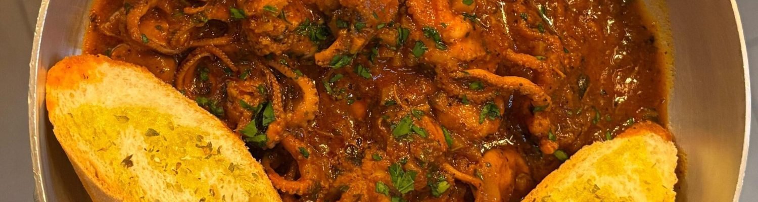 Calamaretti in umido alla genovese serviti con crostini all'aglio, specialità di mare